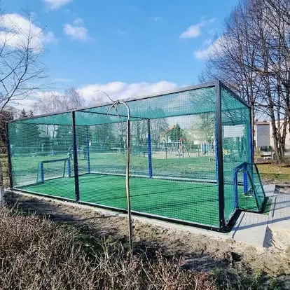 Zamknięte mini boisko Football Box zamontowane przy osiedlowym placu zabaw - bezpieczna gra dzięki siatkom z każdej strony.