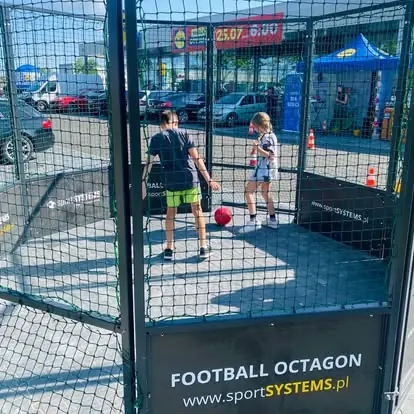 Dzieci grają 1 na 1 w mobilnej arenie Football Octagon podczas eventu promocyjnego przy otwarciu sklepu.