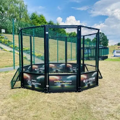 Football Octagon z personalizowanymi bandami reklamowymi zamontowany na gminnym terenie rekreacyjnym.